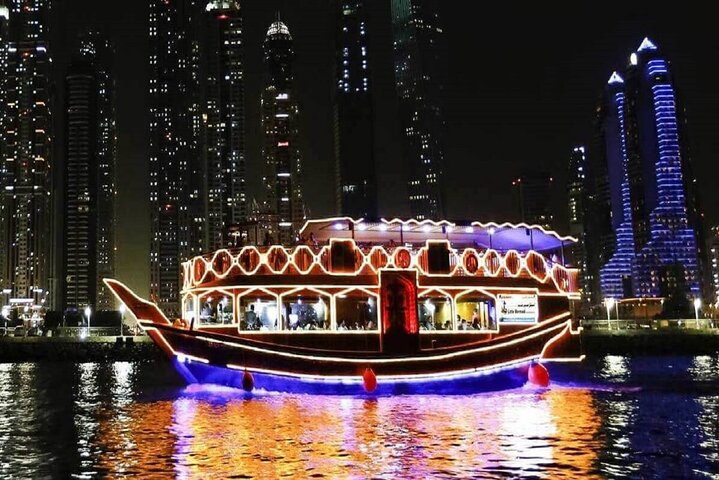 Experience the stunning views of Dubai's skyline while enjoying a delightful dinner aboard a beautifully lit dhow soaking in the city's charm and elegance against the night sky.